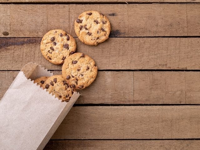 Chocolate chip cookies on a paper bag over a wooden table.