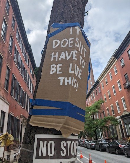 A cardboard sign taped to a telephone pole near where a vehicle killed Children's Hospital of Philadelphia Dr. Barbara Friedes, while cycling home from work on Spruce Street, reads "IT DOESN'T HAVE TO BE THAT WAY!"