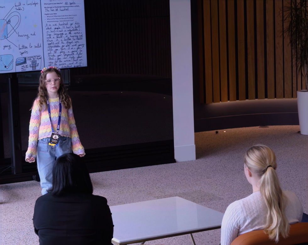 Schoolgirl gives a speech in front of two adults